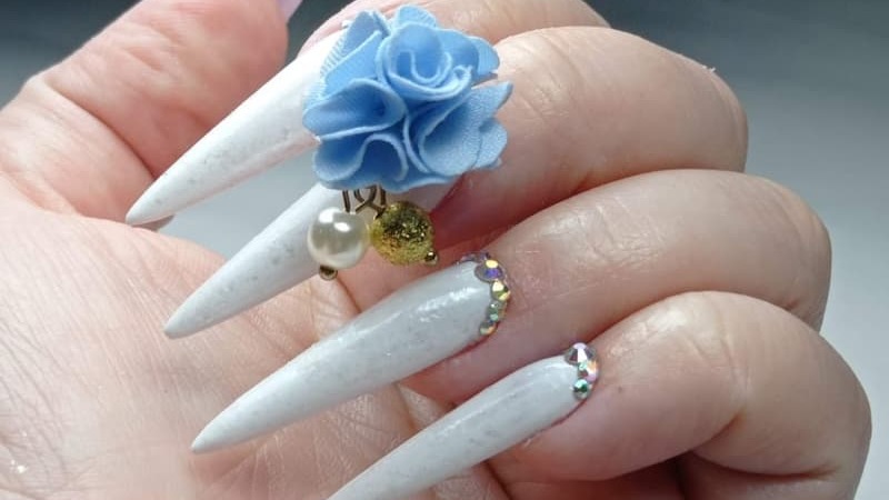 uñas acrílicas stiletto blancas con pompon y diamantes
