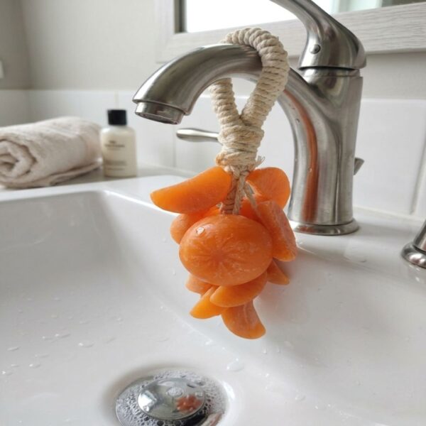 racimo de naranjas de jabón en un grifo de un lavabo